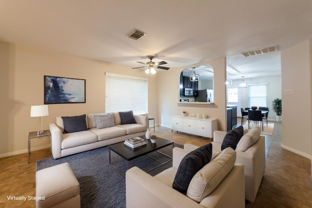 living room with visible vents, baseboards, and a ceiling fan