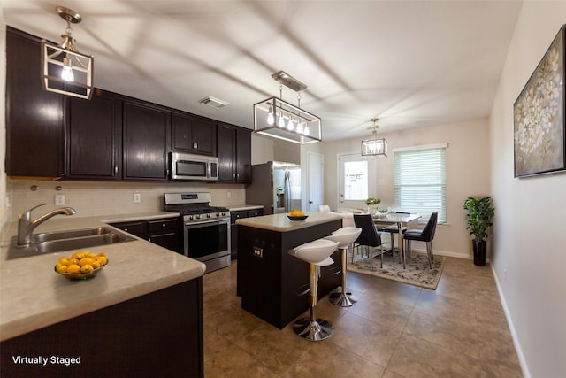 kitchen with visible vents, a kitchen bar, decorative backsplash, appliances with stainless steel finishes, and a sink