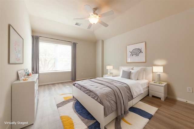 bedroom featuring visible vents, a ceiling fan, baseboards, light wood finished floors, and lofted ceiling