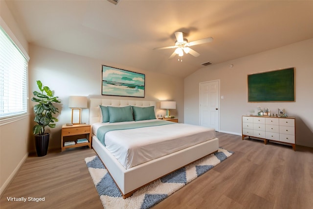 bedroom with lofted ceiling, baseboards, visible vents, and light wood finished floors