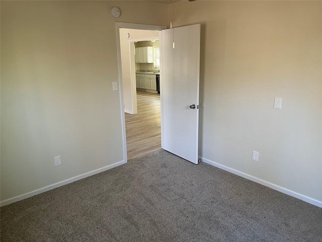 empty room featuring baseboards and light carpet