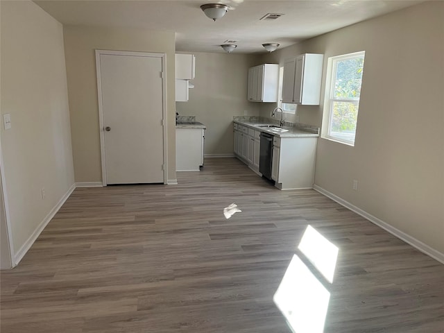 kitchen with light wood-type flooring, visible vents, a sink, light countertops, and dishwashing machine