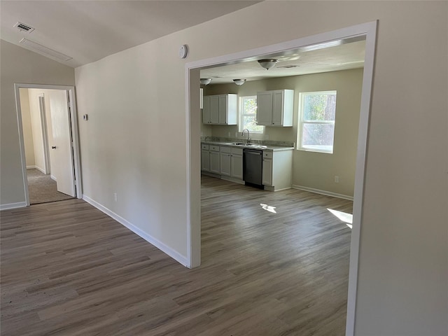 corridor featuring vaulted ceiling, dark wood-style floors, baseboards, and a sink