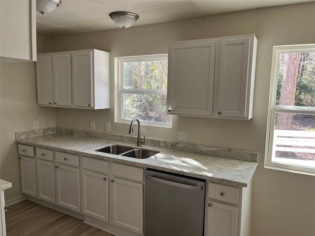 kitchen featuring stainless steel dishwasher, light stone countertops, white cabinetry, and a sink