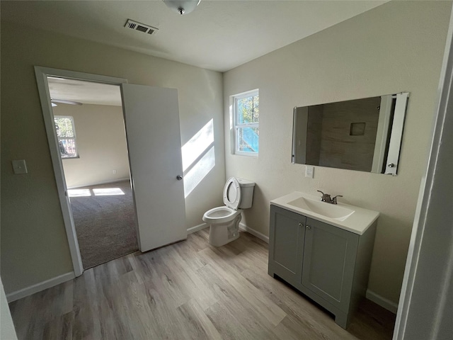 bathroom with visible vents, baseboards, toilet, wood finished floors, and vanity