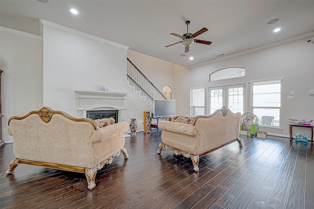 living room featuring a ceiling fan, a glass covered fireplace, ornamental molding, dark wood finished floors, and recessed lighting