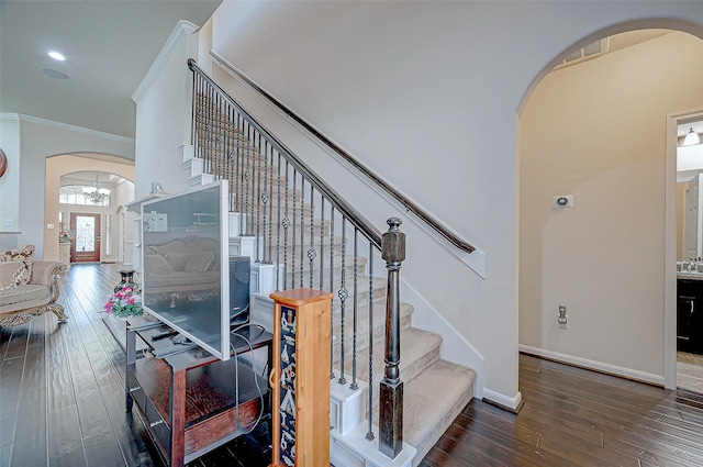 stairs featuring arched walkways, wood-type flooring, crown molding, and baseboards