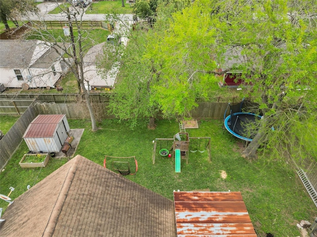 view of yard featuring a trampoline, a fenced backyard, and an outdoor structure