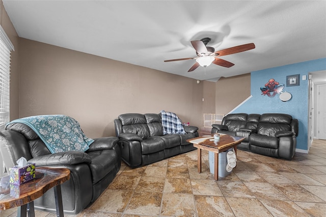 living area featuring stone finish floor, baseboards, and ceiling fan