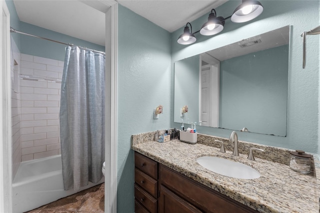 full bathroom featuring visible vents, toilet, shower / bath combo, vanity, and a textured wall