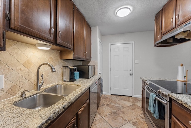 kitchen with tasteful backsplash, light stone countertops, under cabinet range hood, stainless steel appliances, and a sink