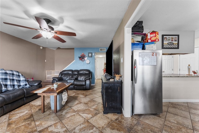 living room with baseboards, visible vents, and ceiling fan