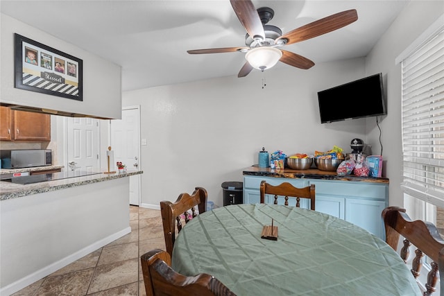 dining room featuring light tile patterned floors, baseboards, and ceiling fan