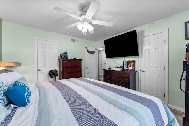 carpeted bedroom with visible vents, baseboards, and a ceiling fan