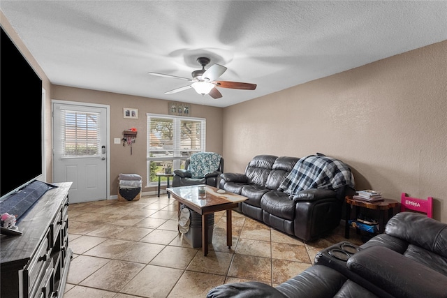 living room featuring a textured ceiling, baseboards, and ceiling fan