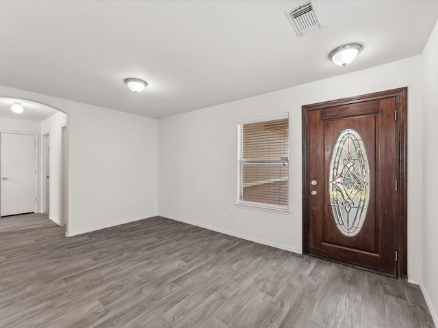 entryway featuring wood finished floors, arched walkways, visible vents, and baseboards