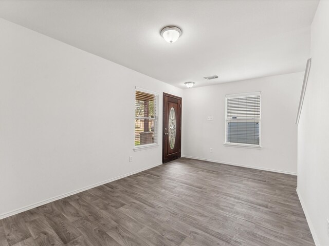 empty room featuring visible vents, baseboards, and wood finished floors