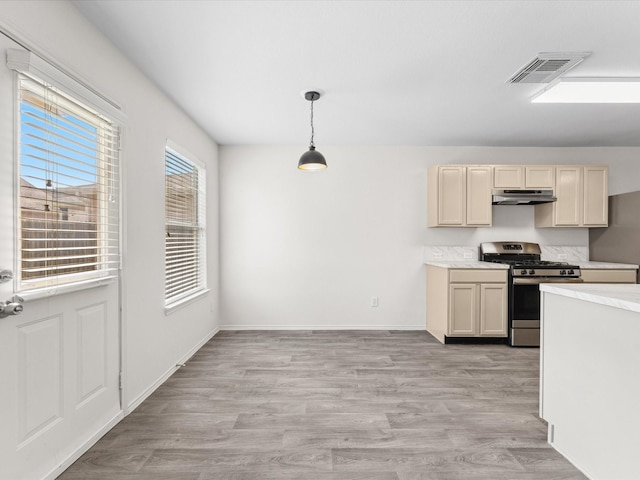 kitchen featuring stainless steel gas range oven, visible vents, light wood-style floors, and under cabinet range hood