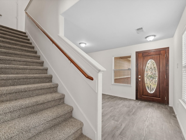 foyer featuring light wood finished floors, visible vents, stairway, and baseboards