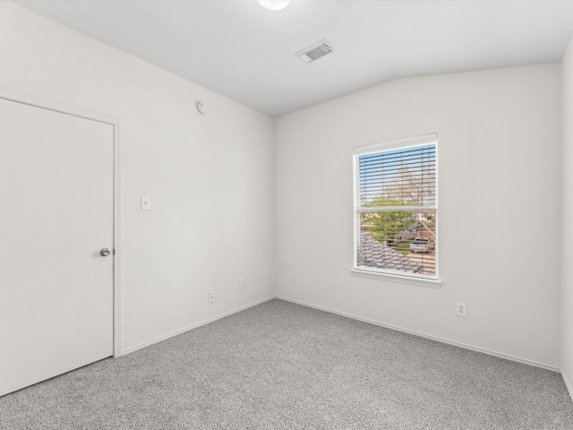 spare room featuring visible vents, lofted ceiling, and carpet flooring