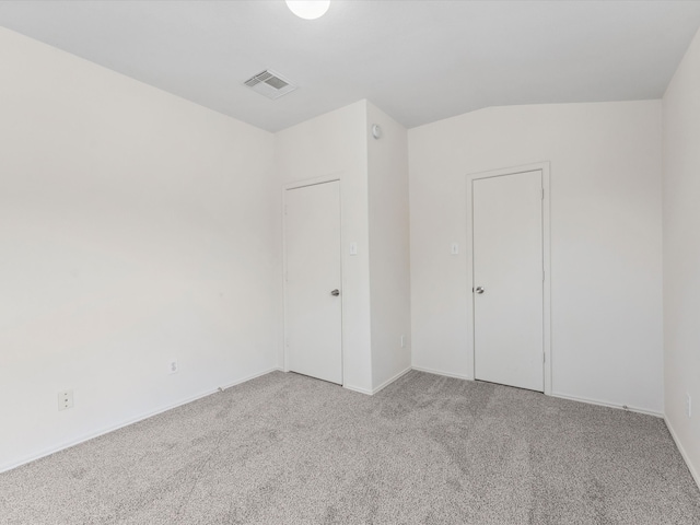 spare room with lofted ceiling, light colored carpet, and visible vents