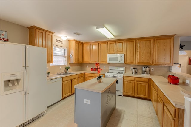 kitchen featuring visible vents, a sink, white appliances, a peninsula, and light countertops