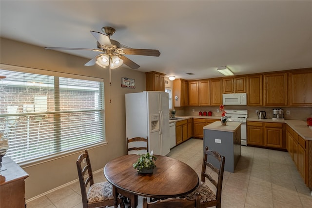 kitchen with a kitchen island, ceiling fan, light countertops, light tile patterned floors, and white appliances