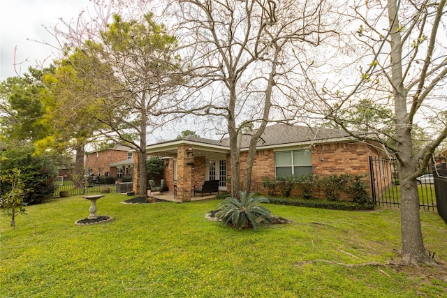 back of house featuring a patio, a lawn, brick siding, and fence