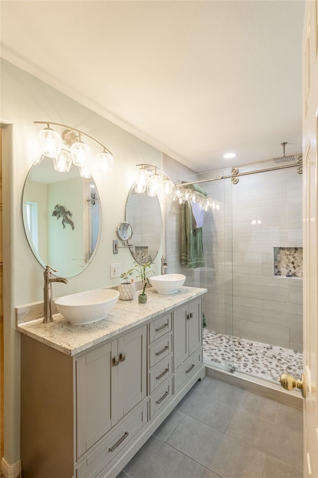 bathroom with a sink, double vanity, a shower stall, and tile patterned floors