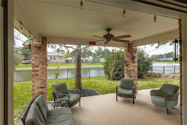 view of patio featuring a fenced backyard, ceiling fan, and a water view