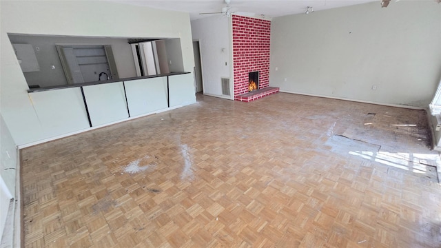 unfurnished living room featuring a brick fireplace, visible vents, and ceiling fan