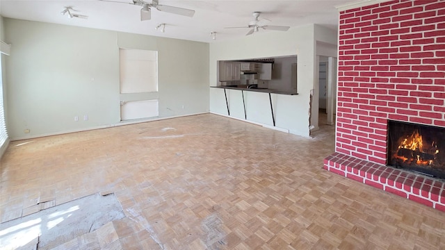 unfurnished living room featuring baseboards, a brick fireplace, and a ceiling fan