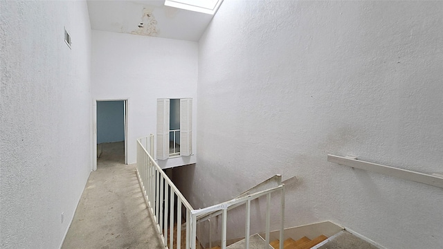 stairs featuring visible vents, concrete flooring, and a textured wall