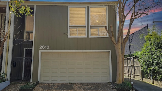 view of front of home with a garage, driveway, and fence