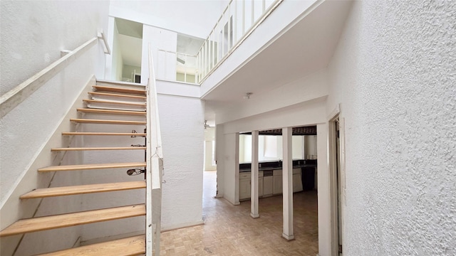 staircase featuring a high ceiling and a textured wall