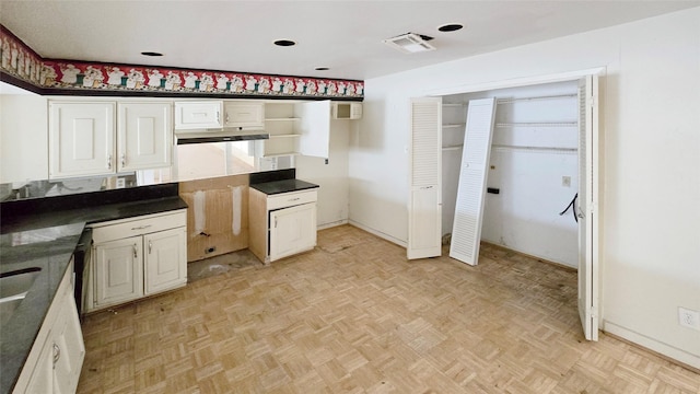 kitchen with dark countertops, visible vents, white cabinets, and baseboards