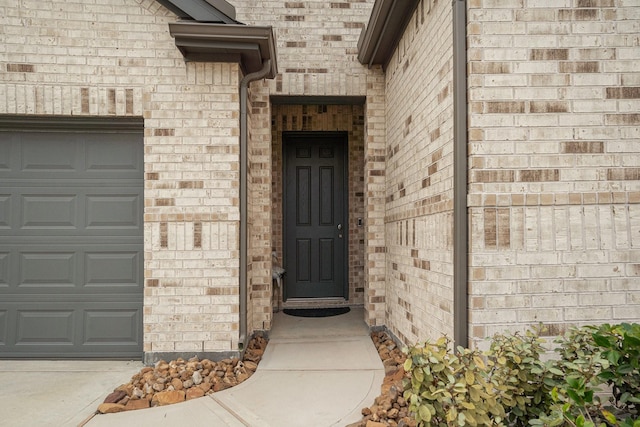 entrance to property with brick siding and a garage