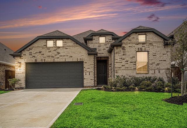 french country style house featuring a garage, a yard, brick siding, and driveway