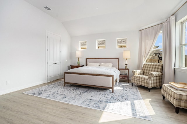 bedroom featuring lofted ceiling, wood finished floors, visible vents, and baseboards