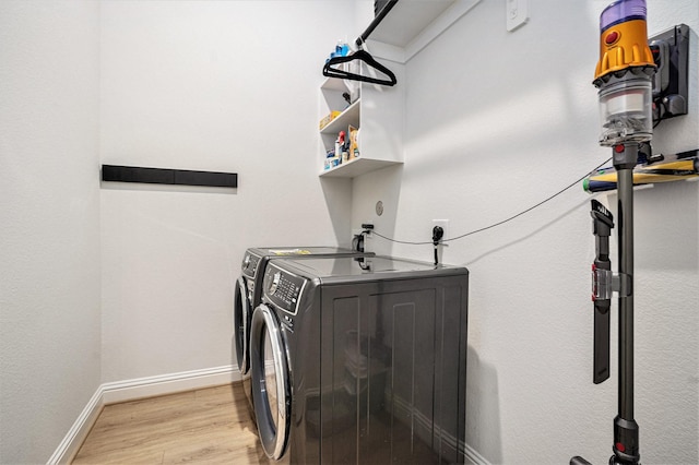 laundry room featuring baseboards, light wood-style floors, laundry area, and washer and clothes dryer