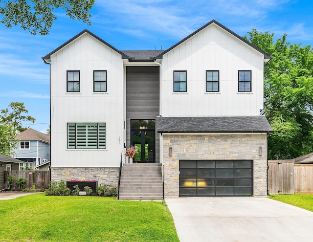 modern farmhouse with stone siding, fence, board and batten siding, a front yard, and a garage