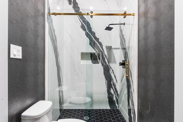 bathroom featuring a marble finish shower, toilet, and tile patterned flooring