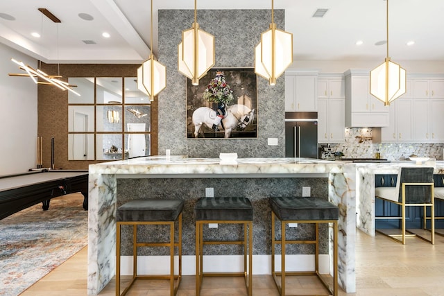 kitchen with decorative backsplash, light wood-style floors, visible vents, and high end fridge