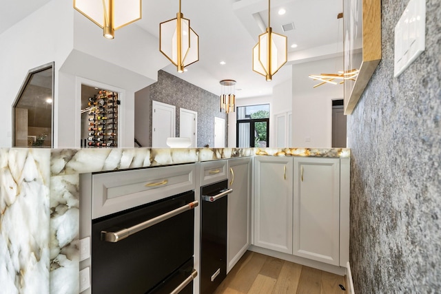 kitchen featuring light stone countertops, visible vents, light wood-style flooring, recessed lighting, and decorative light fixtures