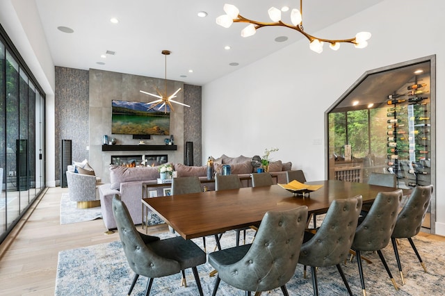 dining space with light wood-style flooring, a notable chandelier, recessed lighting, and a large fireplace