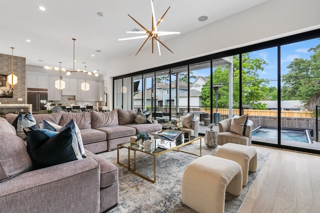 living room featuring recessed lighting, ceiling fan with notable chandelier, and light wood finished floors