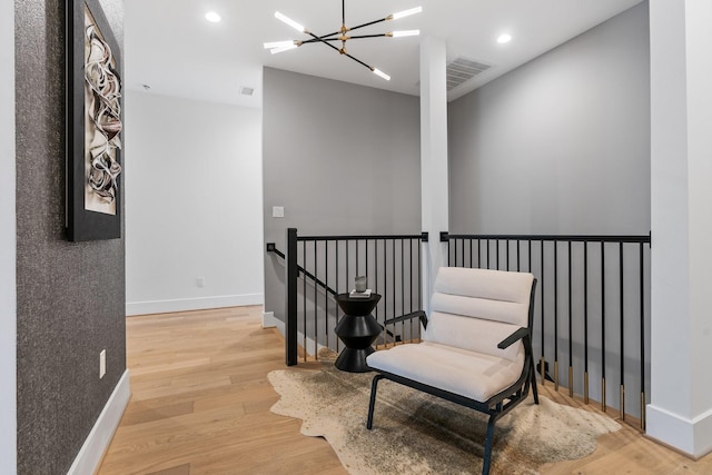 living area featuring baseboards, an upstairs landing, recessed lighting, an inviting chandelier, and wood finished floors