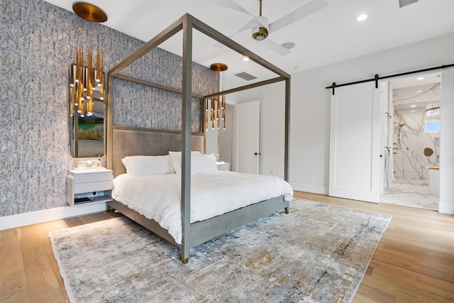 bedroom with visible vents, recessed lighting, a barn door, and wood finished floors