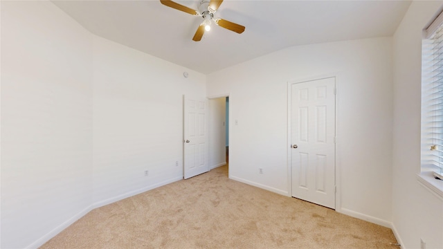 unfurnished bedroom with vaulted ceiling, baseboards, light colored carpet, and ceiling fan