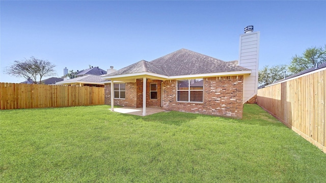back of house featuring a patio, brick siding, a fenced backyard, and a yard